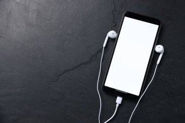 Kulaklıklı akıllı telefon, siyah masa, üst görüş. Metin için boşluk