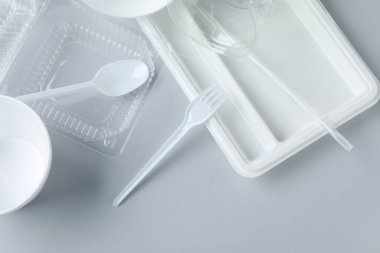 Aydınlık zemin üzerinde farklı plastik kaplar ve kaplar, düz yatıyordu