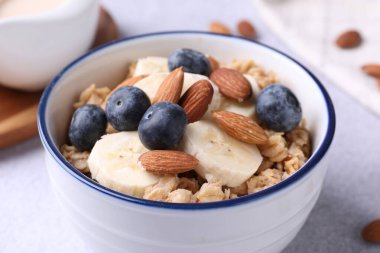 Bademli yulaf ezmesi, yaban mersini ve muz açık gri masada, yakın plan.