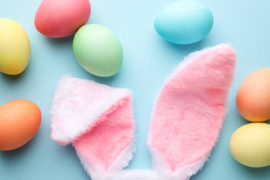 Mutlu Paskalyalar. Şirin tavşan kulakları ve açık mavi arka planda boyanmış yumurtalar.