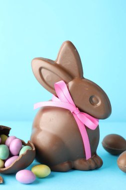 Çikolatalı Paskalya tavşanı ve açık mavi arka planda şekerli yumurta, yakın plan.