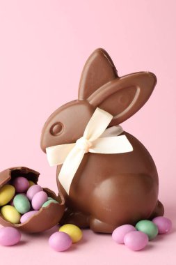 Çikolatalı Paskalya tavşanı ve pembe arka planda şekerli yumurta, yakın plan.