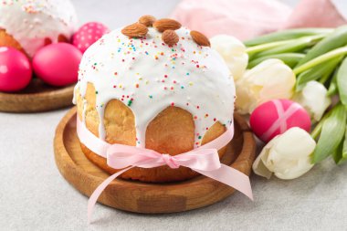 Lezzetli Paskalya pastası, açık gri masada boyanmış yumurta ve laleler, yakın plan.