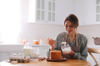 Genç bir kadın geleneksel paskalya pastasını mutfakta jöleli dekore ediyor. Metin için boşluk