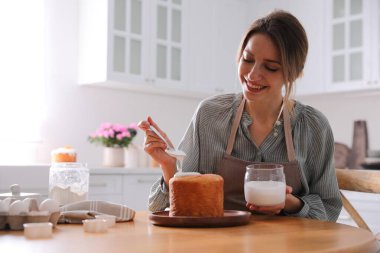 Genç bir kadın geleneksel paskalya pastasını mutfakta jöleli dekore ediyor. Metin için boşluk