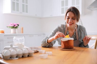 Genç bir kadın geleneksel paskalya pastasını mutfakta süslüyor. Metin için boşluk