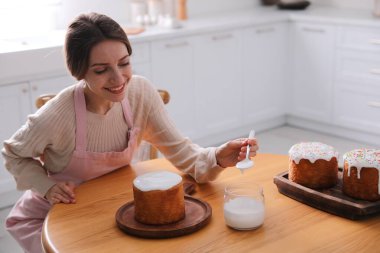 Genç bir kadın geleneksel paskalya pastasını mutfakta jöleli dekore ediyor. Metin için boşluk