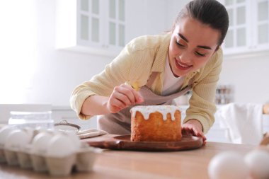 Genç bir kadın geleneksel paskalya pastasını mutfakta serpiştiriyor.