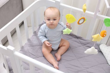 Evinde bebek karyolası olan küçük şirin bir bebek.