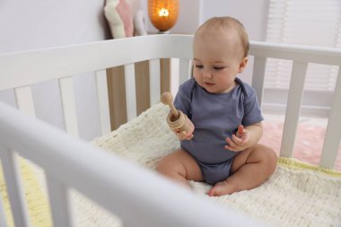 Evinde ahşap çıngıraklı şirin bir bebek.