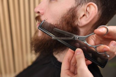 Berber dükkanında adamın sakalını buduyor, yakın plan.