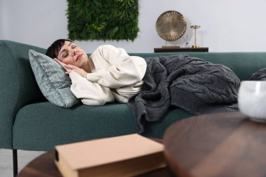 Ekoseyle kaplı bir kadın evdeki kanepede kestiriyor.