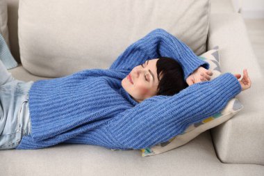 Güzel bir kadın evdeki kanepede kestiriyor.