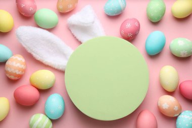 Mutlu Paskalyalar. Şirin tavşan kulakları, boyalı yumurtalar ve pembe arka planda boş podyum, düz yatış. Metin için boşluk