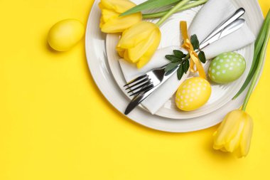 Paskalya kutlaması. Lale çiçekli şenlik masası ve sarı arka planda boyanmış yumurtalar, düz yatak. Metin için boşluk