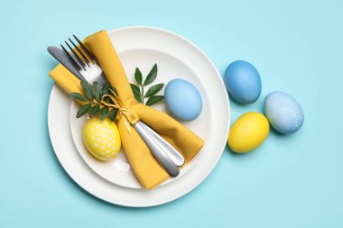 Paskalya kutlaması. Yeşil yapraklı şenlik masası ve açık mavi arka planda boyanmış yumurtalar.