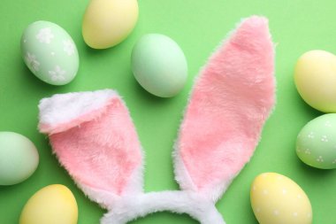 Mutlu Paskalyalar. Şirin tavşan kulakları ve yeşil arka planda boyanmış yumurtalar.
