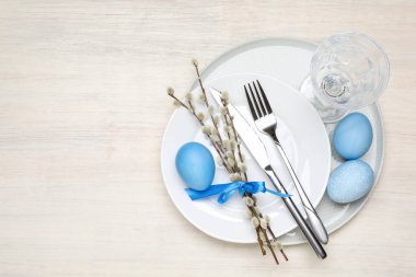 Beyaz ahşap arka planda Paskalya yumurtaları ve söğüt dallarıyla şenlik masası manzarası. Metin için boşluk