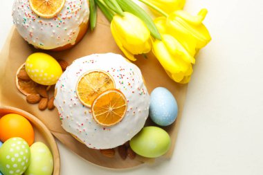 Lezzetli Paskalya pastaları, laleler ve beyaz masaya boyanmış yumurtalar. Metin için boşluk