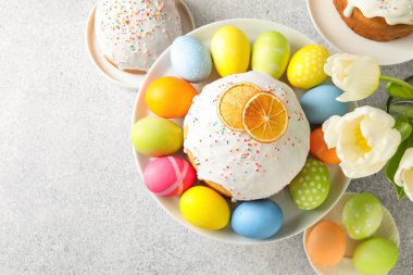 Lezzetli Paskalya pastaları, laleler ve açık gri masaya boyanmış yumurtalar. Metin için boşluk