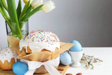 Lezzetli Paskalya pastaları, beyaz ahşap masada boyanmış yumurta ve laleler, yakın plan. Metin için boşluk