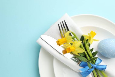 Paskalya kutlaması. Nergis çiçekleri ve açık mavi arkaplan üzerine boyanmış yumurta içeren şölen masası, üst manzara. Metin için boşluk