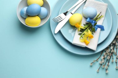 Paskalya kutlaması. Üzerinde nergis çiçekleri, boyalı yumurtalar ve açık mavi arka planda söğüt dalları olan şenlik masası düzlüğü. Metin için boşluk