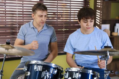 Genç çocuk içeride müzik öğretmeniyle bateri çalmayı öğreniyor.