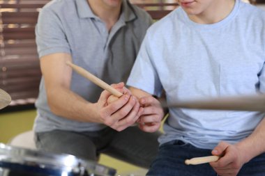 Genç çocuk bateri çalmayı öğreniyor içeride müzik öğretmeniyle, yakın plan