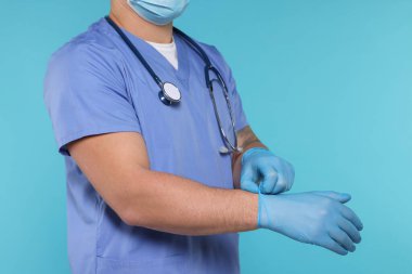 Açık mavi arka planda eldiven takan tıp çalışanı, yakın plan. Metin için boşluk