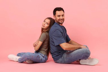 Pembe arka planda baba ve kızının portresi.