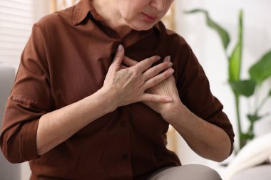 Kalp krizi geçirdi. Üst düzey kadın göğüs ağrısı çekiyor. Kapalı bir yerde, yakın plan.