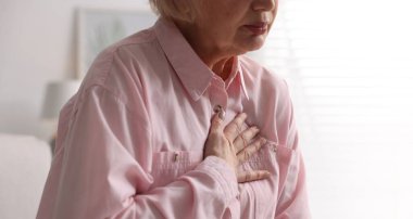 Kalp krizi geçirdi. Üst düzey kadın göğüs ağrısı çekiyor. Kapalı bir yerde, yakın plan.