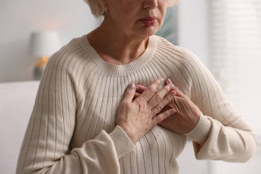Kalp krizi geçirdi. Üst düzey kadın göğüs ağrısı çekiyor. Kapalı bir yerde, yakın plan.