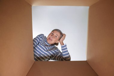 İçeriden karton kutuya bakan düşünceli bir kadın, içeriden bakan.