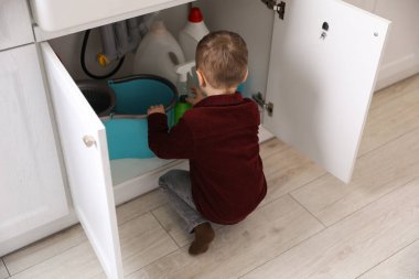 Evde çocuk güvenliği. Küçük çocuk mutfakta temizlik ürünleriyle oynuyor.