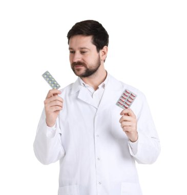 Beyaz arka planda ilaç kabarcıkları olan ceketli profesyonel bir eczacı.