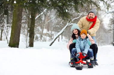 Mutlu bir aile kış günü dışarıda kızakla eğleniyor, mesaj atmak için yer var.