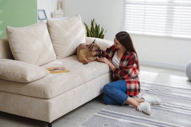 Evdeki kanepenin yanında sevimli köpeği olan bir kadın.