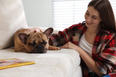 Evdeki kanepenin yanında sevimli köpeği olan bir kadın.