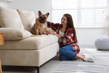 Evdeki kanepenin yanında sevimli köpeği olan bir kadın.