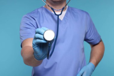 Açık mavi arka planda steteskobu olan doktor, seçici odak