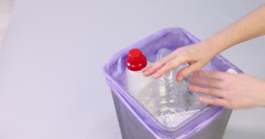 Açık gri arka planda plastik ambalajı çöp kutusuna atan kadın, yakın plan