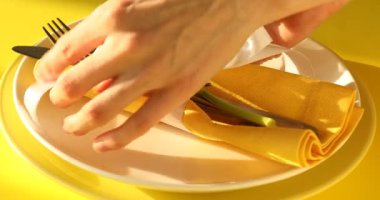 Paskalya kutlaması. Sarı arka planda akşam yemeği için masa hazırlayan kadın, yakın plan.