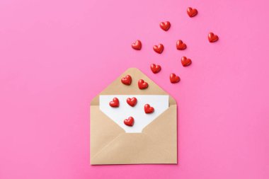 Tebrik kartı ve pembe arka planda dekoratif kalpler içeren zarf, düz uzanma