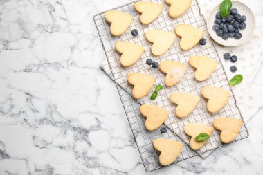 Lezzetli kalp şeklinde tereyağlı kurabiyeler, nane ve yaban mersini beyaz mermer masa, düz yatak. Metin için boşluk