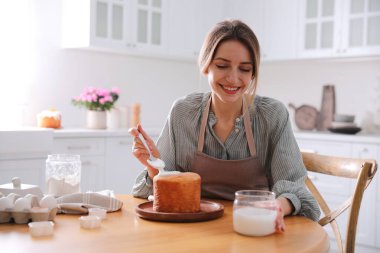 Genç bir kadın geleneksel paskalya pastasını mutfakta jöleli dekore ediyor. Metin için boşluk
