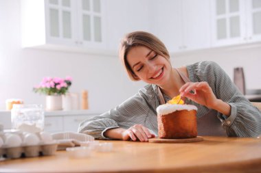 Genç bir kadın geleneksel paskalya pastasını mutfakta süslüyor. Metin için boşluk