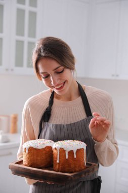 Young woman with traditional Easter cakes in kitchen