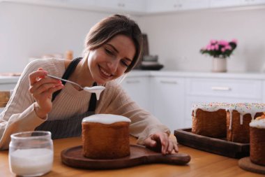 Genç bir kadın geleneksel paskalya pastasını mutfakta jöleli dekore ediyor. Metin için boşluk